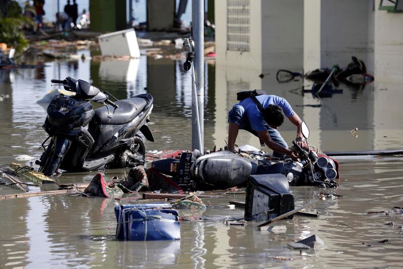 An Indonesian man tries to get his motorbike upright in Talise beach, Palu, Central Sulawesi, Indonesia.  EPA