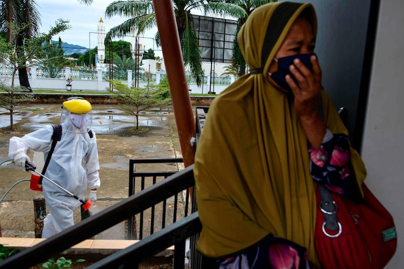 A worker disinfects a bus stop in Banda Aceh, Indonesia. AFP