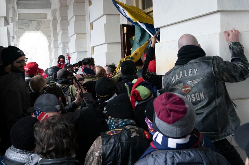 FILE - In this Jan. 6, 2021 file photo insurrectionists loyal to President Donald Trump try to open a door of the U.S. Capitol as they riot in Washington. At least a dozen of the 400 people charged so far in the Jan. 6 insurrection have made dubious claims about their encounters with officers at the Capitol. The most frequent argument is that they can't be guilty of anything, because police stood by and welcomed them inside, even though the mob pushed past police barriers, sprayed chemical irritants and smashed windows as chaos enveloped the government complex.  (AP Photo/Jose Luis Magana, File)