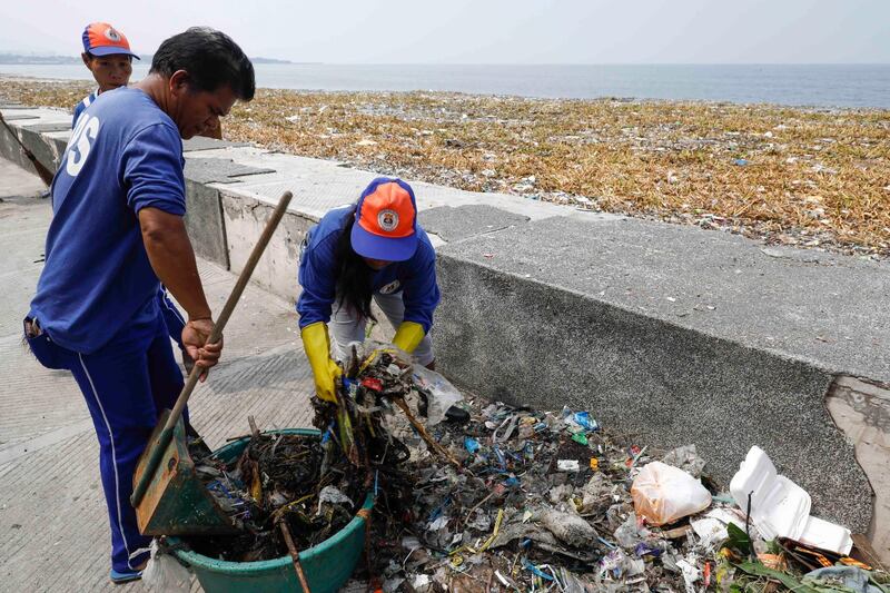 Government workers collect trash and debris along the shore of Manila Bay as part of typhoon precautions in Manila. EPA