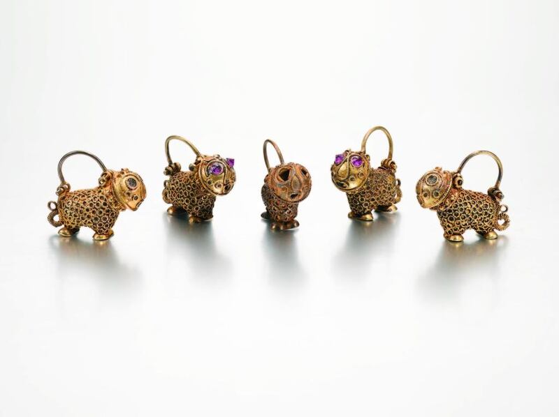 A set of five lion-form gold earrings, Persia, 12th centuryEstimate: £6,000- 8,000each composed of gold, designed as stylised lions decorated with twisted wire, hinged hook for hanging, two with later-inset pink stones to eyes Quantity: 5each: 1.9cm. height.