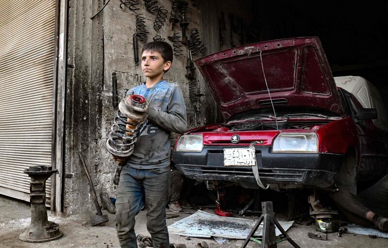 A young Syrian boy works at a car repair shop in the town of Jandaris, in the countryside of the northwestern city of Afrin in the rebel-held part of Aleppo province, on June 11, 2022, a day before the annual World Day Against Child Labour.  (Photo by Rami al SAYED  /  AFP)