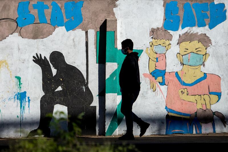 epa08974736 A man with face mask walks in front of mural depicting two persons wearing face protective masks amid the ongoing coronavirus COVID-19 pandemic in Cairo, Egypt, 30 January 2021.  EPA/MOHAMED HOSSAM