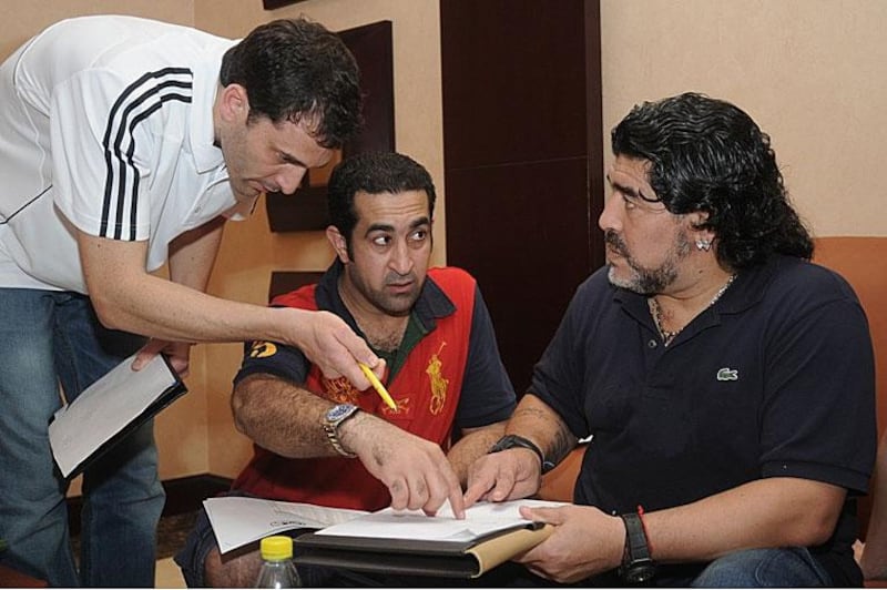 Ali Hussain, second, left, signs a contract to become assistant coach to Diego Maradona.