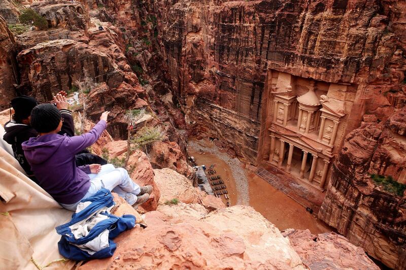 FILE - In this Feb. 13, 2017 file photo, tourists point at the Treasury, in the kingdom's Petra archaeological park, southern Jordan. A fictional caper about an antiquities heist set Petra has stirred widespread outrage over the filmâ€™s portrayal of historical Jewish ties to Jordan, shining a light on the tenuous peace with neighboring Israel and prompting the government to suspend the movieâ€™s production. â€œJaberâ€ follows a Jordanian boy who uncovers a stone with a Hebrew inscription on it in the rose-colored, rock-hewn city of Petra. (AP Photo/Sam McNeil, File)