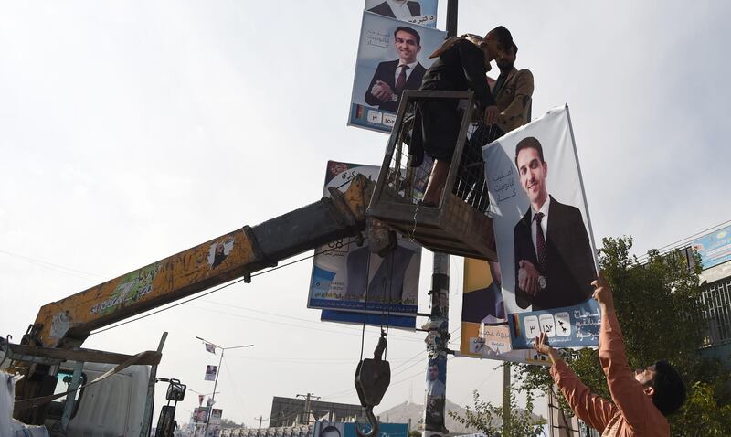 Labourers hang banners of candidate Alhaj Abdull Qayoum Khairkhah on a post along the street in Kabul. AFP