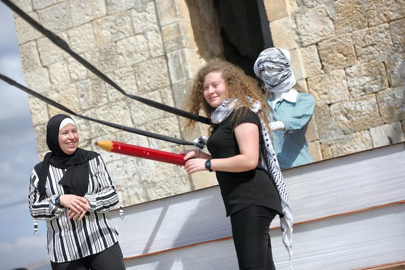 Ahed with her mother at the city center of their village with an installation depicting a female stone thrower in her village nebi salah 