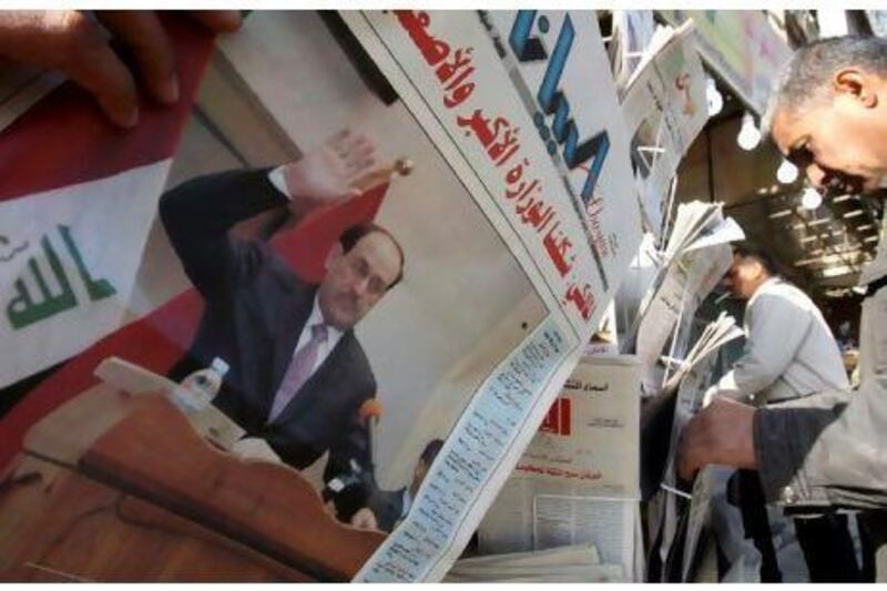 Iraqis pick up newspapers yesterday featuring a front-page story on the inauguration of the new government. Ali al-Saadi / AFP