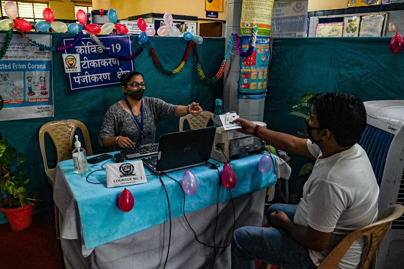 A health worker, left, registers a man for a dose of the Covaxin vaccine in New Delhi. Prakash Singh / AFP