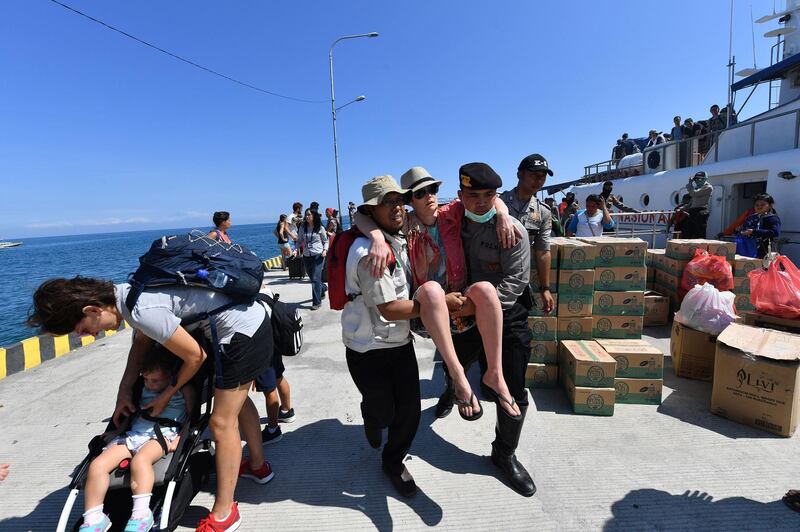 A foreign tourist is given assistance as people arrive from nearby Gili Trawangan island.  AFP Photo