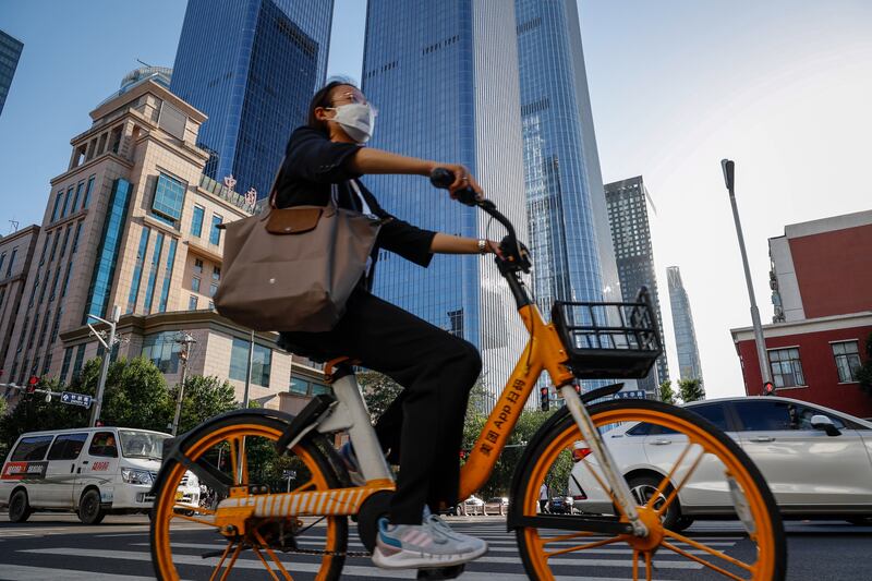 A woman rides a bicycle in the central business district of Beijing. China's surveyed unemployment rate eased to 5.5 per cent from May's 5.9 per cent. EPA
