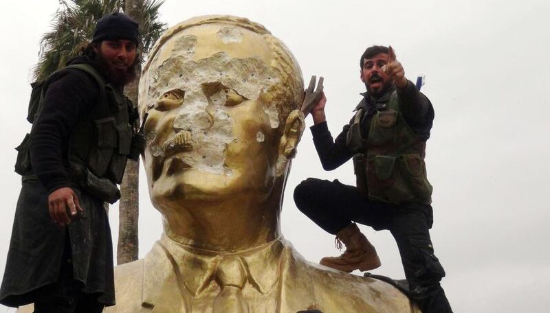 Rebel fighters deface a statue of the late Syrian president Hafez Al Assad in Idlib city on March 28, 2015. Sami Ali / AFP