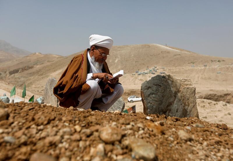 An Afghan cleric prays over the grave of one of the victims of yesterday's suicide attack. Reuters