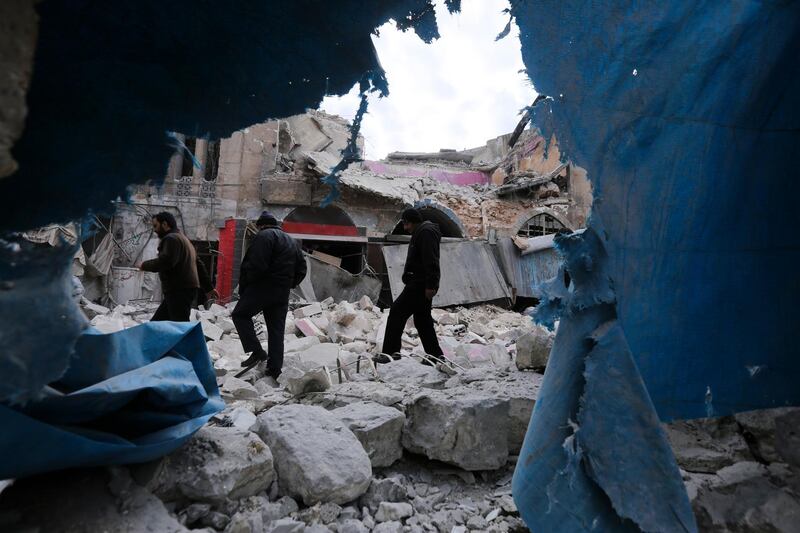 People walk past destruction by the government airstrikes in the town of Ariha. AP Photo