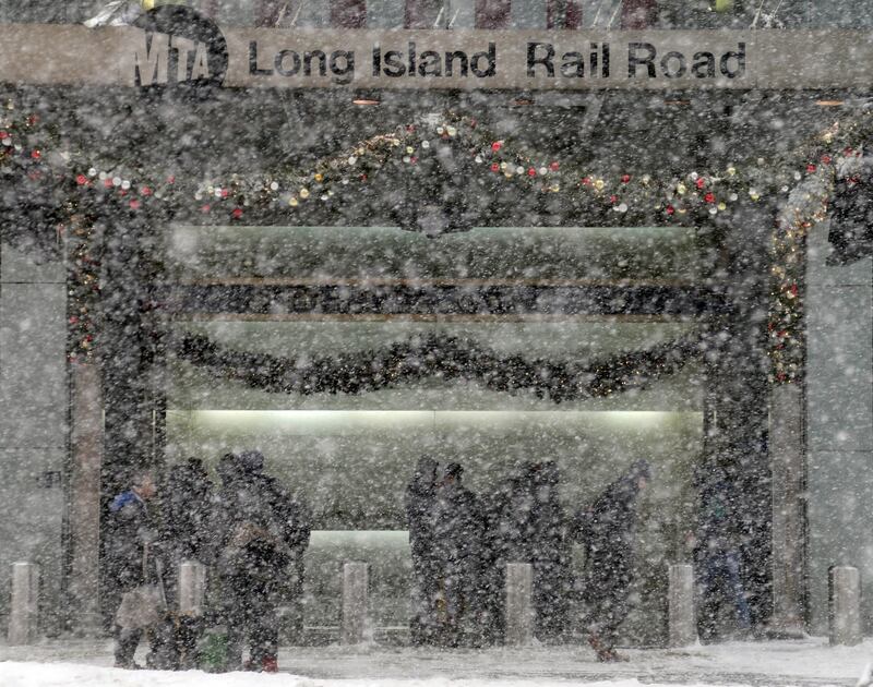 Pedestrians get out of the snow storm by standing at the entrance of the Long Island Railroad. Seth Wenig / AP Photo