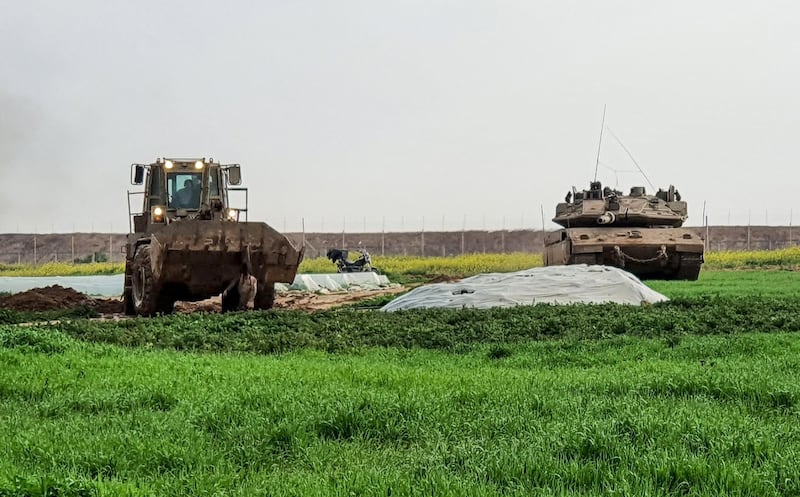 An Israeli bulldozer carrying a body of a Palestinian, shot dead by Israeli forces after he was suspected of placing a bomb, along the Gaza-Israel border in Gaza strip. AFP