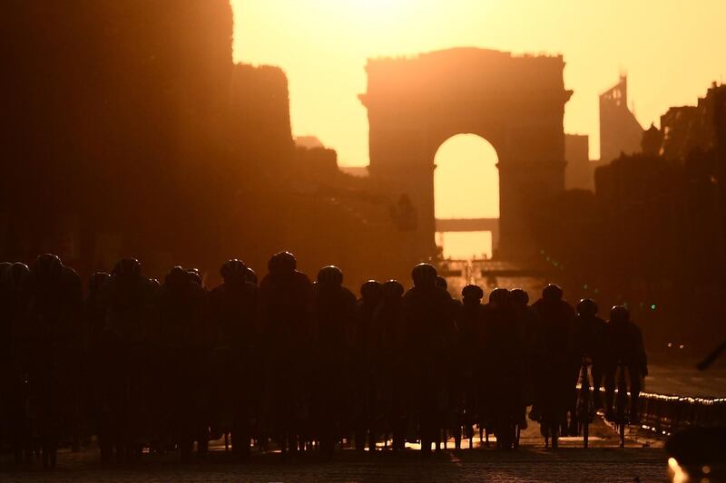 Cyclists ride dwon the Champs Elysees avenue with the Arc de Triomphe in background.  AFP