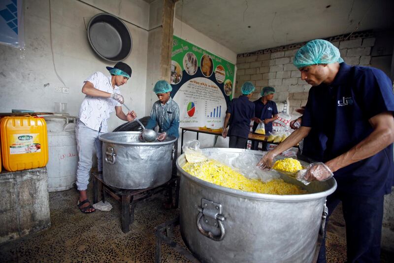 Cooks pack food at a charity kitchen, which gives free food rations for the poor, in Sanaa, Yemen April 20, 2018. REUTERS/Mohamed al-Sayaghi