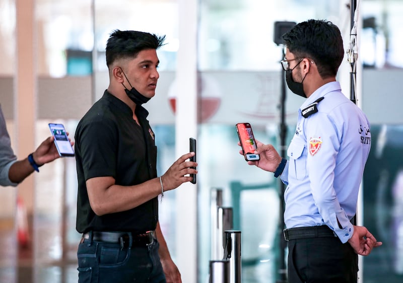 Al Wahda Mall security staff check the Al Hosn app of visitors at the entrance. All photos: Victor Besa / The National