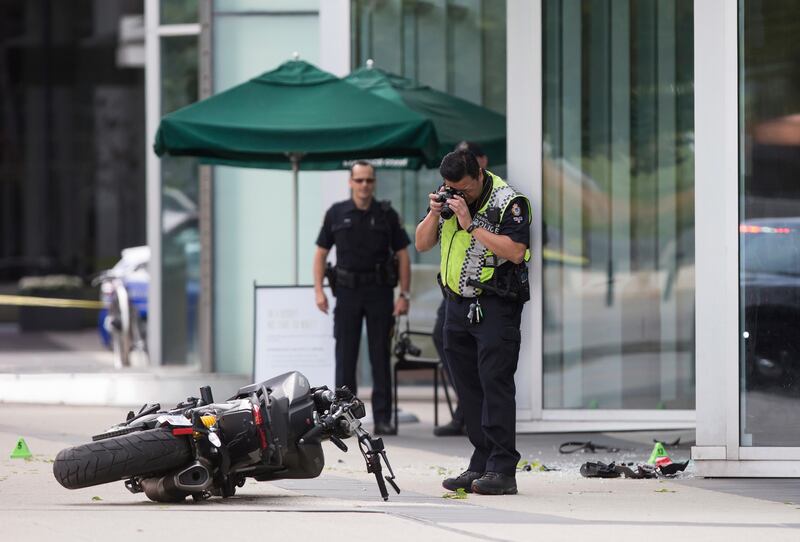 A police officer photographs a motorcycle after a female stunt driver working on the movie "Deadpool 2" died after a crash on set, in Vancouver, B.C., on Monday Aug. 14, 2017. Vancouver police say the driver was on a motorcycle when the crash occurred on the movie set on Monday morning. (Darryl Dyck/The Canadian Press via AP)