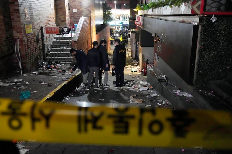 Police officers inspect the scene where people died and were injured in Itaewon. AP