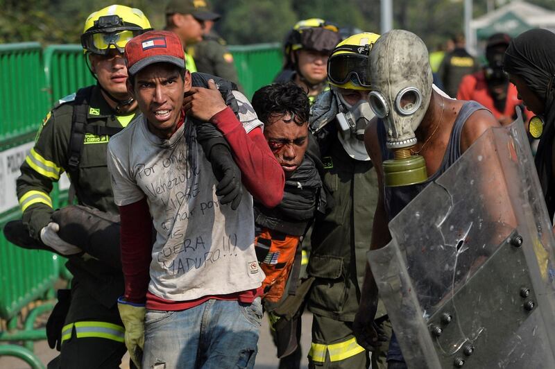 TOPSHOT - A demonstrator is being assisted on the Simon Bolivar International Bridge in Cucuta, Colombia, after being wounded during clashes with Venezuelan security forces across the border in San Antonio del Tachira, Venezuela, on February 25, 2019. United States Vice President Mike Pence told Venezuelan opposition leader Juan Guaido that Donald Trump supports him "100 percent" as the pair met regional allies on Monday to thrash out a strategy to remove Nicolas Maduro from power after the failed attempt to ship in humanitarian aid. / AFP / Luis ROBAYO
