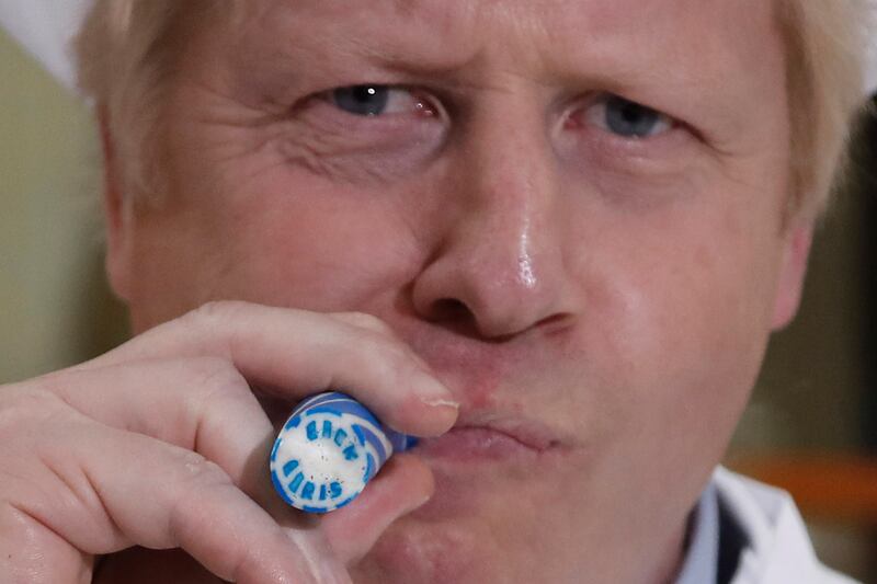 Mr Johnson eats a rock sweet which reads 'Back Boris' during a general election campaign trail stop in Blackpool, in November 2019. Getty Images