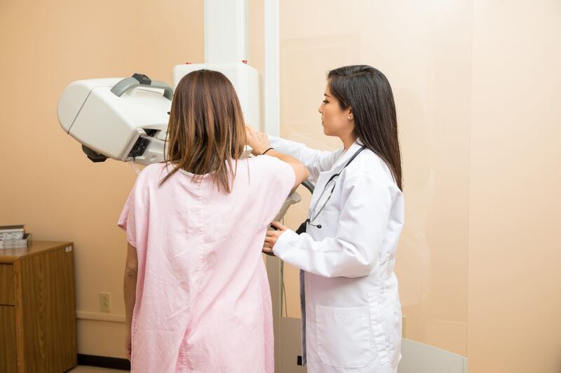 A woman is scanned for breast cancer using a mammogram