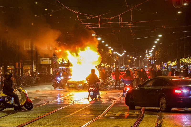 A car is set on fire in Amsterdam as a crowd gathers after the Morocco victory over Belgium. EPA