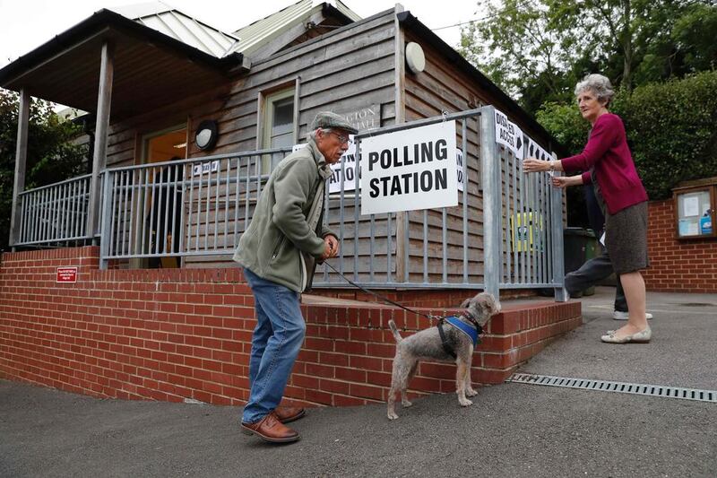 A voter brings his dog as the polling officer fixes the sign outside the polling station at Garsington Village Hall in Garsington, Oxford.  AFP