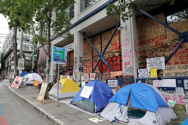 Tents, signs, and graffiti remain, Wednesday, June 24, 2020, in front of the Seattle Police East Precinct building inside the CHOP (Capitol Hill Occupied Protest) zone in Seattle. The area has been occupied since a police station was largely abandoned after clashes with protesters, but Seattle Mayor Jenny Durkan said Monday that the city would move to wind down the protest zone following several nearby shootings and other incidents that have distracted from changes sought peaceful protesters opposing racial inequity and police brutality. (AP Photo/Ted S. Warren)