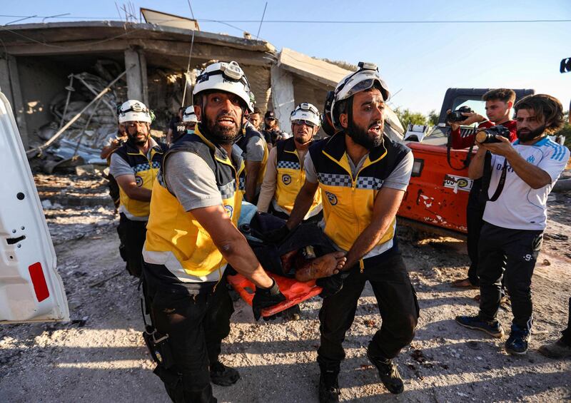 Members of the Syrian Civil Defence, also known as the "White Helmets", carry away a body on a stretcher following a reported government air strike in the village of Benin, about 30 kilometres south of Idlib in northwestern Syria.  AFP
