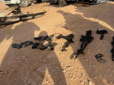 Rifles and ammunition on the ground near the damaged lorry. 