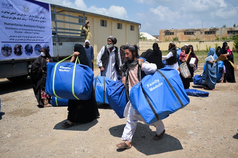 People carry aid distributed by the International Organisation for Migration and the United States Agency for International Development after flash floods triggered by heavy rains in Herat, Afghanistan. AFP