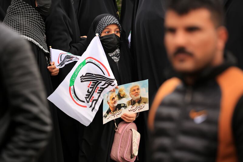 A PMF follower carries the organisation’s flag and portraits of Al Muhandis and Suleimani. EPA