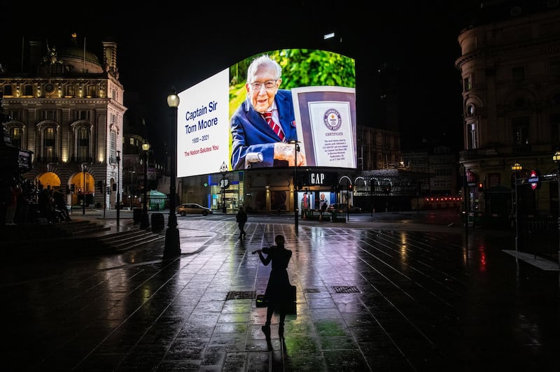 A violinist plays in front of a tribute to Captain Sir Tom Moore at Piccadilly Circus shortly after it was announced that he had died on February 2. Getty Images