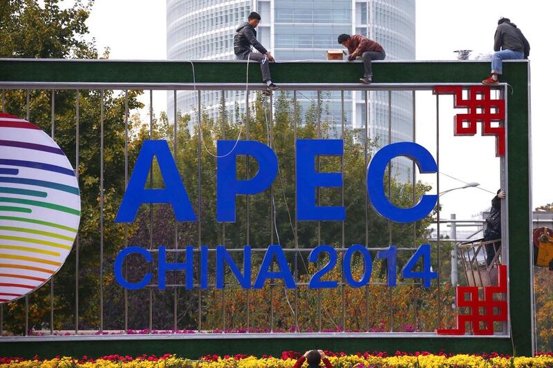 A man takes pictures of workers installing lighting on an APEC sign post at the financial district in Beijing, on October 28, 2014. Countries at an Asia-Pacific summit in Beijing pledged to pursue "flexible" fiscal policies to support the world economy and job creation, their finance ministers said in a joint statement on Wednesday. Petar Kujundzic / Reuters