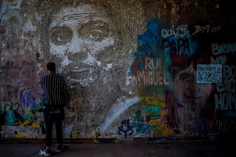 A man stands in front of an artwork in memory of Brazilian activist Marielle Franco by Portuguese artist Vhils at the Monsanto panoramic viewpoint during the Iminente Festival in Lisbon. AFP