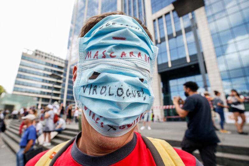 A demonstrator wearing a face mask over his face with the words 'Mascarade, Virologues' takes part in a protest against health measures made by the Belgian government over the coronavirus disease (COVID-19) pandemic, in Brussels, Belgium. The group of demonstrators does not deny the existence of the coronavirus but disputes its degree of contagiousness and its lethality and does not want to wear masks.  EPA