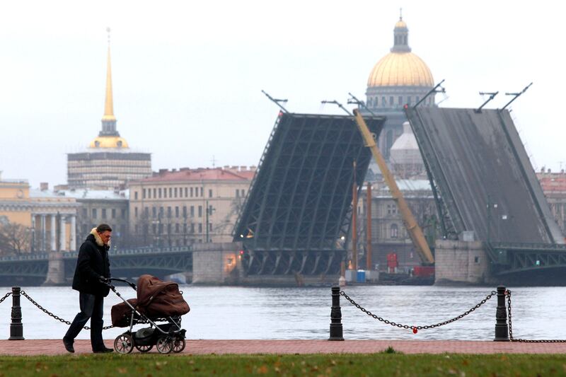 A man pushes a pram along an embankment close to the Palace Bridge, unusually open to allow repair work, in St. Petersburg, November 24, 2012. Russia's second city is famous for its drawbridges which open at night to allow shipping traffic to pass along the River Neva.  REUTERS/Alexander Demianchuk (RUSSIA - Tags: SOCIETY CITYSPACE TRAVEL) - RTR3ATFB