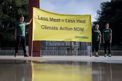 Greenpeace activits hold a banner reading 'less meat : less heat, climate action now', during a protest prior to the publication by The UN's Intergovernmental Panel on Climate Change (IPCC) of a special report on climate change and land on August 8, 2019 in Geneva.  Humanity faces increasingly painful trade-offs between food security and rising temperatures within decades unless it curbs emissions and stops unsustainable farming and deforestation, a landmark climate assessment said the IPCC. / AFP / FABRICE COFFRINI
