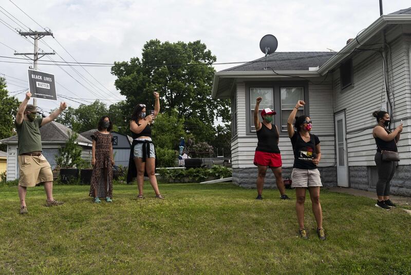 People stand with raised fists as protesters march by while demonstrating against the death of George Floyd in Minneapolis, Minnesota. AFP