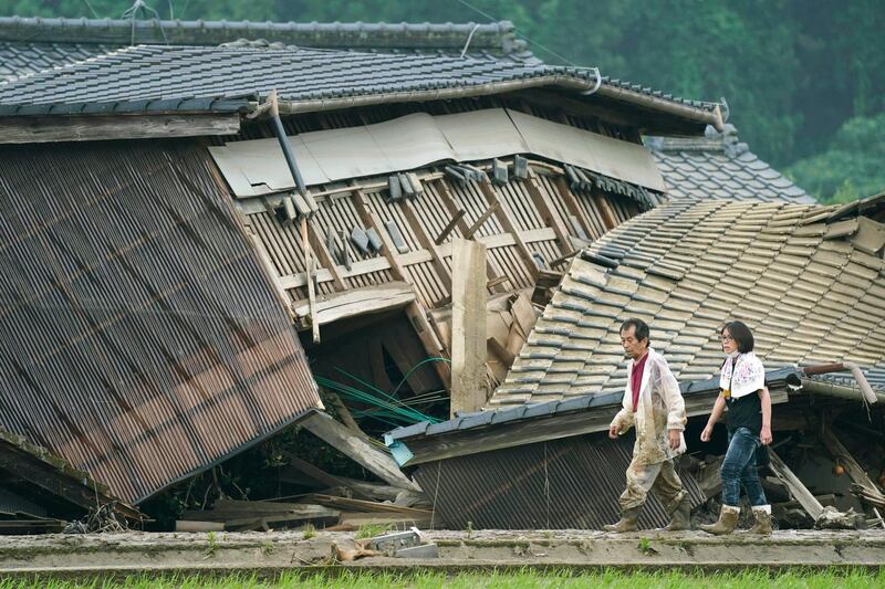A couple walks in front of houses damaged by flood in Kuma village, Kumamoto prefecture, southwestern Japan. AP