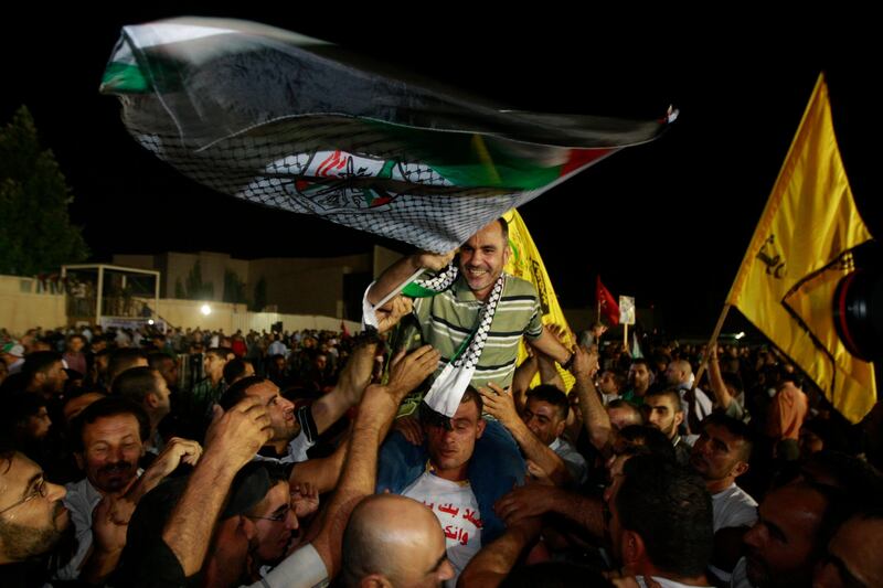 A released Palestinian prisoner Esmat Mansour, center, waves a flag as he is cheered at the Palestinian Authority headquarters in the West Bank city of Ramallah, Wednesday, Aug. 14 , 2013. Israel released 26 Palestinian inmates, including many convicted in grisly killings, on the eve of long-stalled Mideast peace talks, angering families of those slain by the prisoners, who were welcomed as heroes in the West Bank and Gaza. (AP Photo/Majdi Mohammed) *** Local Caption ***  Mideasr Israel Palestinians.JPEG-0ae1a.jpg