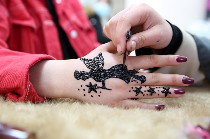 A close-up of a fairy henna tattoo being drawn on a girl's hand by Palestinian henna tattoo artist Samah Sidr, at her shop in the West Bank city of Hebron. EPA