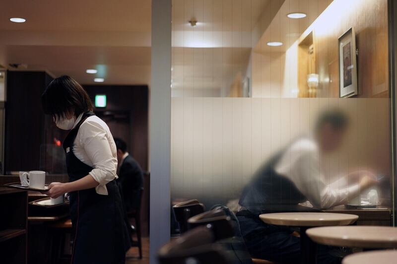 An employee carries empty cups at a cafe in Tokyo, Japan. AP Photo