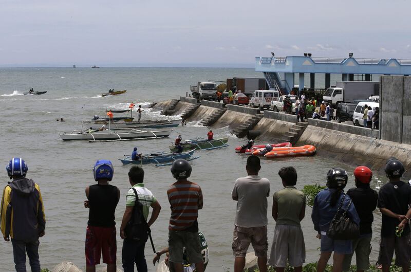 A crowd watches as divers continue their search and rescue operation off Talisay coast, Cebu province Sunday, Aug. 18, 2013 following Friday night's collision of the passenger ferry MV Thomas Aquinas and the cargo ship MV Sulpicio Express Siete in central Philippines. Divers plucked two more bodies from the sunken passenger ferry on Sunday and scrambled to plug an oil leak in the wreckage after a collision with a cargo ship. The accident near the central Philippine port of Cebu that has left 34 dead and more than 80 others missing. (AP Photo/Bullit Marquez) *** Local Caption ***  Philippines Ferry Collision.JPEG-0ec32.jpg