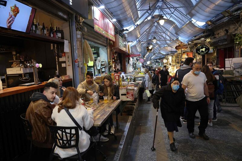 People eat at a restaurant in Jerusalem's main market after authorities reopened restaurants, bars and cafes to "green pass" holders (proof of having received a covid-19 vaccine), on March 11, 2021.  / AFP / Emmanuel DUNAND
