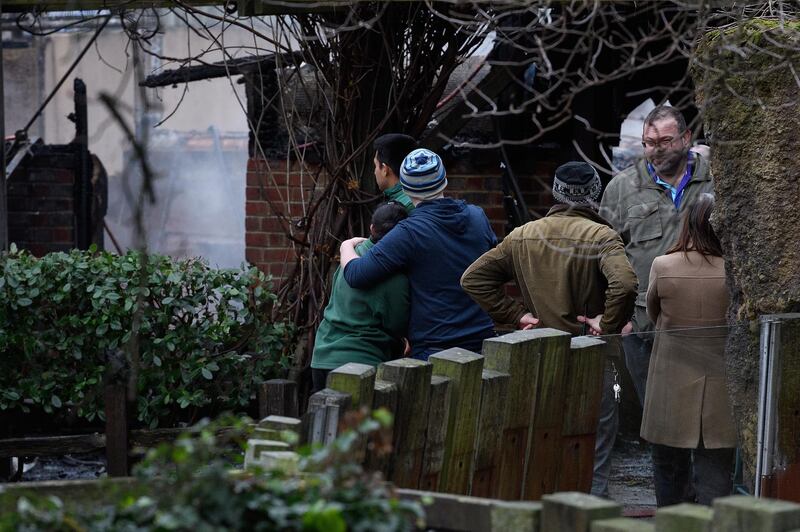 Staff members console each other as they survey the damage after a fire destroyed a number of buildings at London Zoo. Leon Neal / Getty Images.