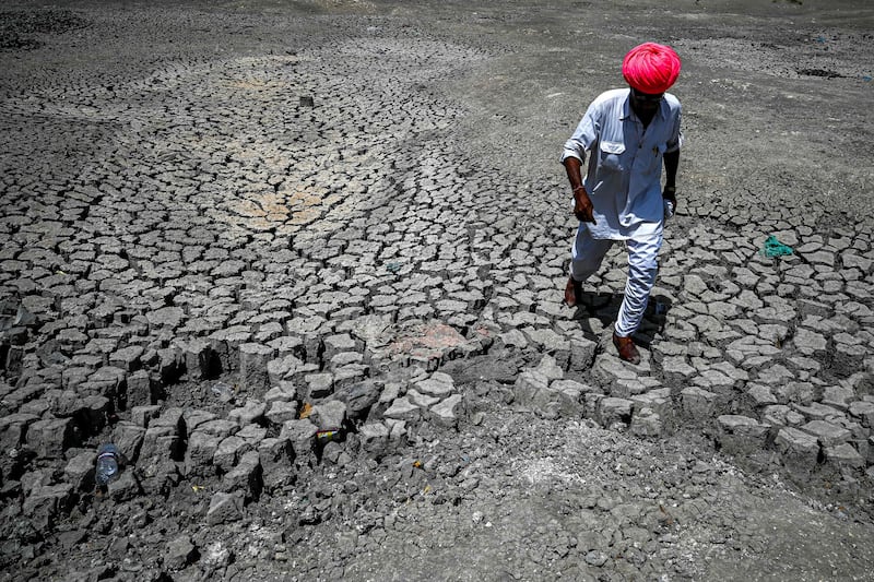 A villager walks through the cracked bottom of a dried-out pond on a hot summer day at Bandai village in Pali district, Rajasthan, last week. AFP